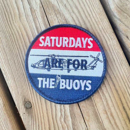 A round patch with a blue background featuring a red and white design and the text 'Saturdays are for the Buoys' along with an image of a helicopter.