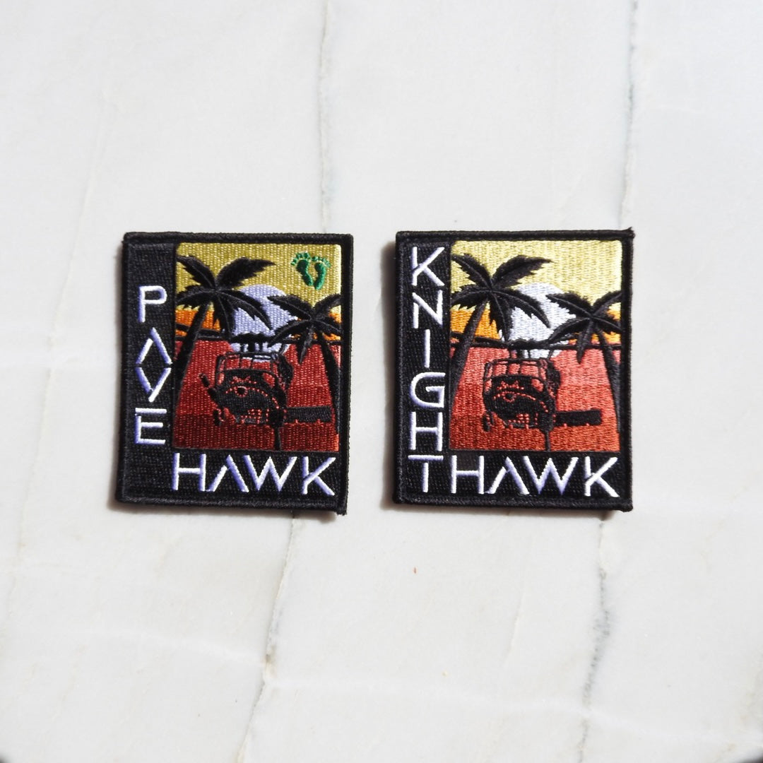 Two embroidered patches, one labeled 'PAVE HAWK' featuring an image of a bird in flight with a sunset and palm trees in the background, and the other patch labeled 'KIGHT HAWK' with a mirrored image of the previous patch.